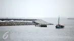 Sebuah kapal nelayan melintas diatas bebatuan tanggul pemecah ombak di Pantai Ancol, Jakarta, Minggu (24/4/2016). Tanggul ini diperuntukan mencegah banjir rob yang sudah sering menimpa daerah Jakarta Utara dan sekitarnya.(Liputan6.com/Faizal Fanani)