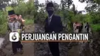 Terlihat pengantin pria dan rombongan keluarga berbondong-bondong melewati jalanan yang becek dan tanpa aspal.