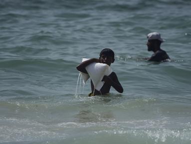 Seorang pemuda Palestina membawa karung bantuan yang mendarat di Laut Mediterania setelah diterbangkan melalui udara di atas pusat kota Gaza, di pantai Zawaida, Jalur Gaza, Selasa, 29 Juli 2025. (AP Photo/Abdel Kareem Hana)