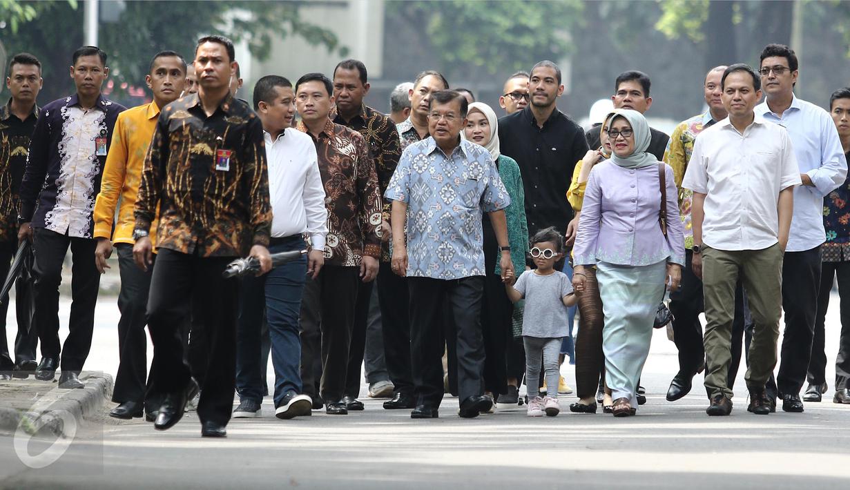 Wakil Presiden Jusuf Kalla (JK) didampingi istri, Mufidah Kalla, menuntun cucunya menuju TPS 03 Kelurahan Pulo, Jakarta Selatan, Rabu (19/4). Di TPS bernuansa Betawi itu, JK memberikan suaranya pada Pilkada DKI putaran kedua (Liputan6.com/Herman Zakharia)