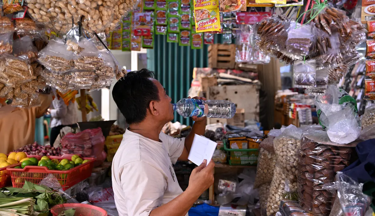 Seorang pedagang meminum air sambil menunggu pelanggan saat cuaca panas melanda Jakarta pada 7 Mei 2024.
ADEK BERRY / AFP
