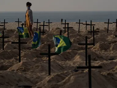 Seorang perempuan berjalan di antara ratusan kuburan di pantai Copacabana, Rio de Janeiro, Kamis (11/6/2020). Aksi simbolis yang dilakukan oleh kelompok LSM Rio de Paz itu sebagai bentuk protes atas respons pemerintah Brasil dalam menangani pandemi Covid-19. (AP Photo/Leo Correa)