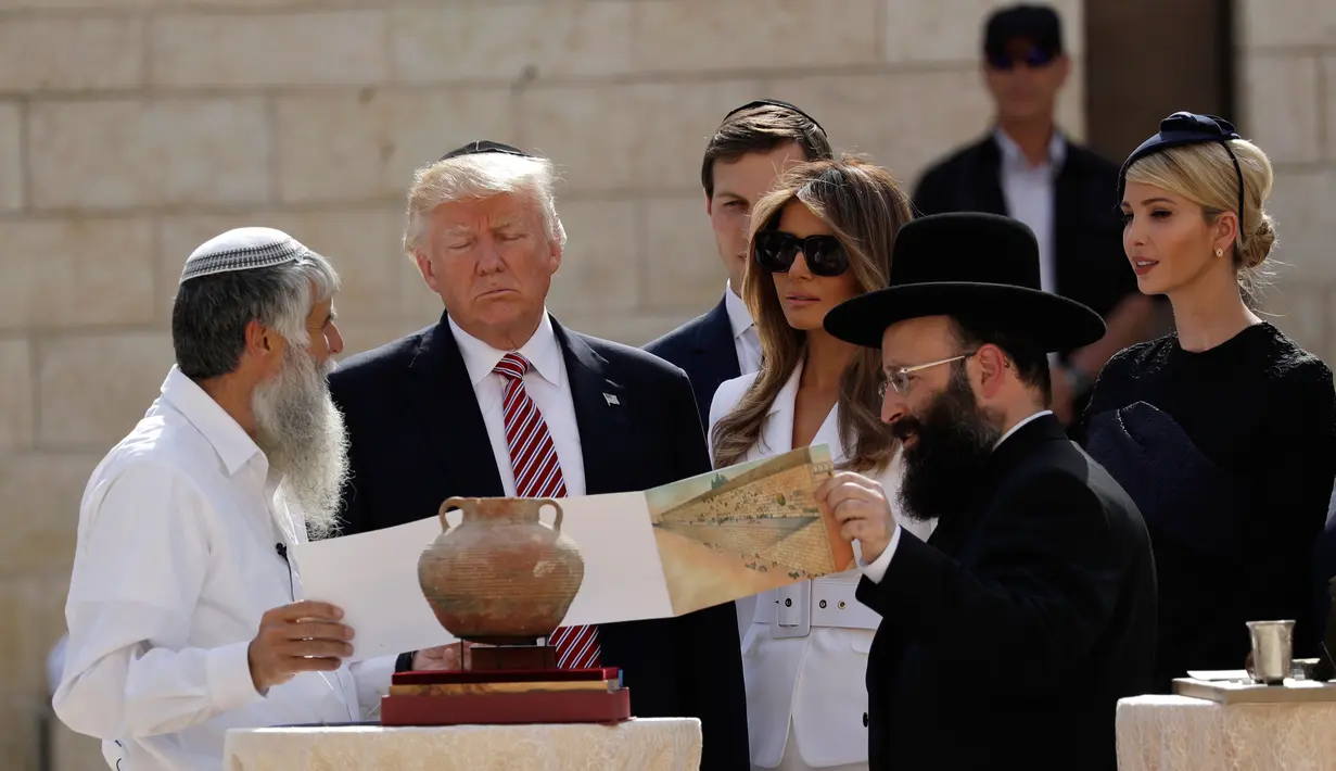 Presiden AS Donald Trump didampingi Ibu Negara, Melania dan Ivanka Trump serta sang suami, Jared Kushner, mendengarkan penjelasan Rabi atau guru Yahudi, Shmuel Rabinowitz saat mengunjungi Tembok Ratapan di Yerusalem, Senin (22/5). (AP Photo/Evan Vucci)