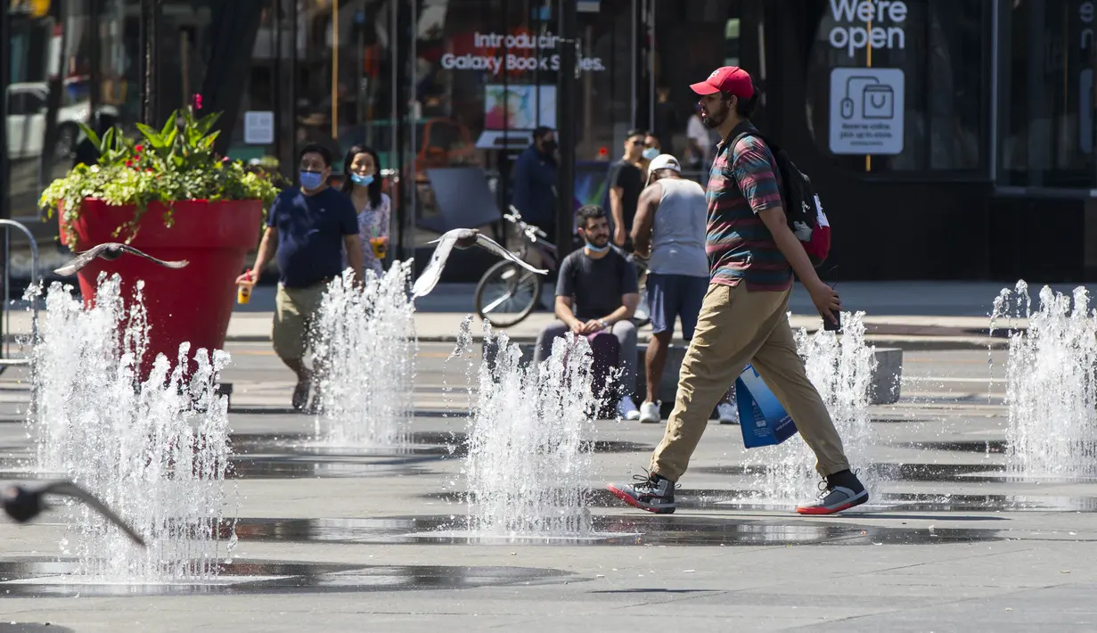 Seorang pria berjalan melewati air mancur di Yonge-Dundas Square di Toronto, Kanada (23/8/2020). Departemen Lingkungan dan Perubahan Iklim Kanada mengeluarkan peringatan cuaca panas untuk Toronto dengan suhu yang diperkirakan akan melonjak dengan suhu terendah mencapai 30-an. (Xinhua/Zou Zheng)