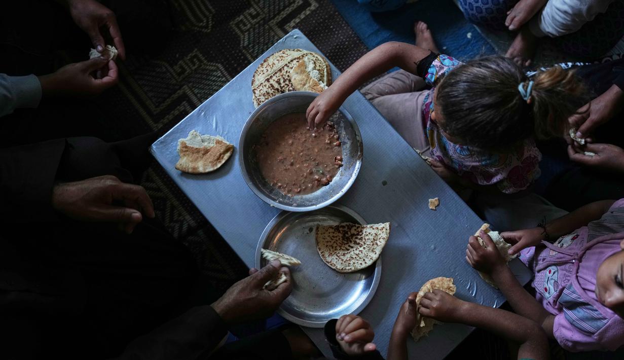 Keluarga Thabet menikmati sarapan di dalam tenda tempat mereka berlindung di Khan Younis, di Jalur Gaza Selatan, Rabu 27 Mei 2026. (Foto AP/Abdel Kareem Hana)