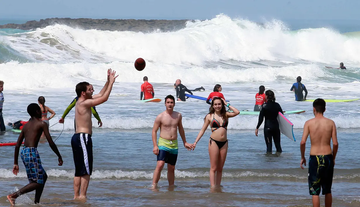 Orang-orang bermain di pantai Port Vieux, (Old Seaport) di Biarritz, barat daya Prancis, (19/4). Suhu di Prancis barat daya telah mencapai 27 derajat Celcius (80,6 Fahrenheit). (AP Photo / Bob Edme)