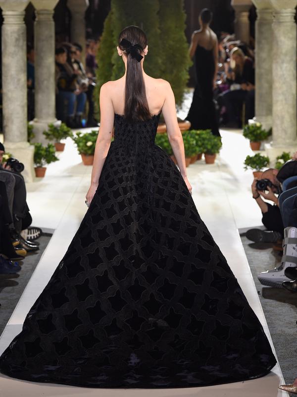 Model Bella Hadid mengenakan gaun hitam koleksi terbaru dari Oscar de la Renta berjalan di atas catwalk selama New York Fashion Week, AS (12/2). Gaun yang dikenakan Bella Hadid dihiasi motif simetris. (AFP Photo/Slaven Vlasic)