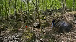 Suad Keserovic dan bola batu temuannya di dalam hutan di Desa Podunavlje, Zavidovici, Bosnia dan Herzegovina, Senin (11/4). Pria itu mengklaim bola batu berdiameter 3,30 meter tersebut memiliki berat sekitar 35 ton. (REUTERS/Dado Ruvic)