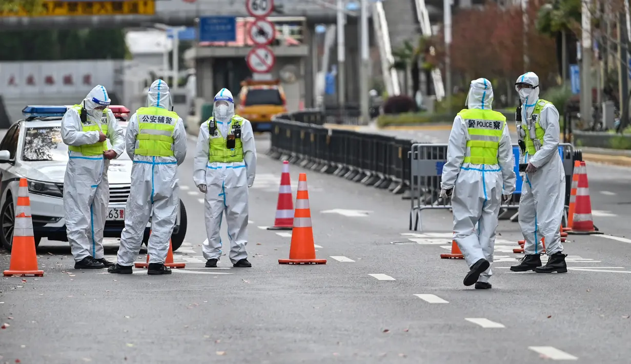 Petugas polisi yang mengenakan pakaian pelindung mengontrol akses ke terowongan ke arah distrik Pudong yang dikunci sebagai tindakan melawan virus corona Covid-19, di Shanghai (28/3/2022). (AFP/Hector Retamal)