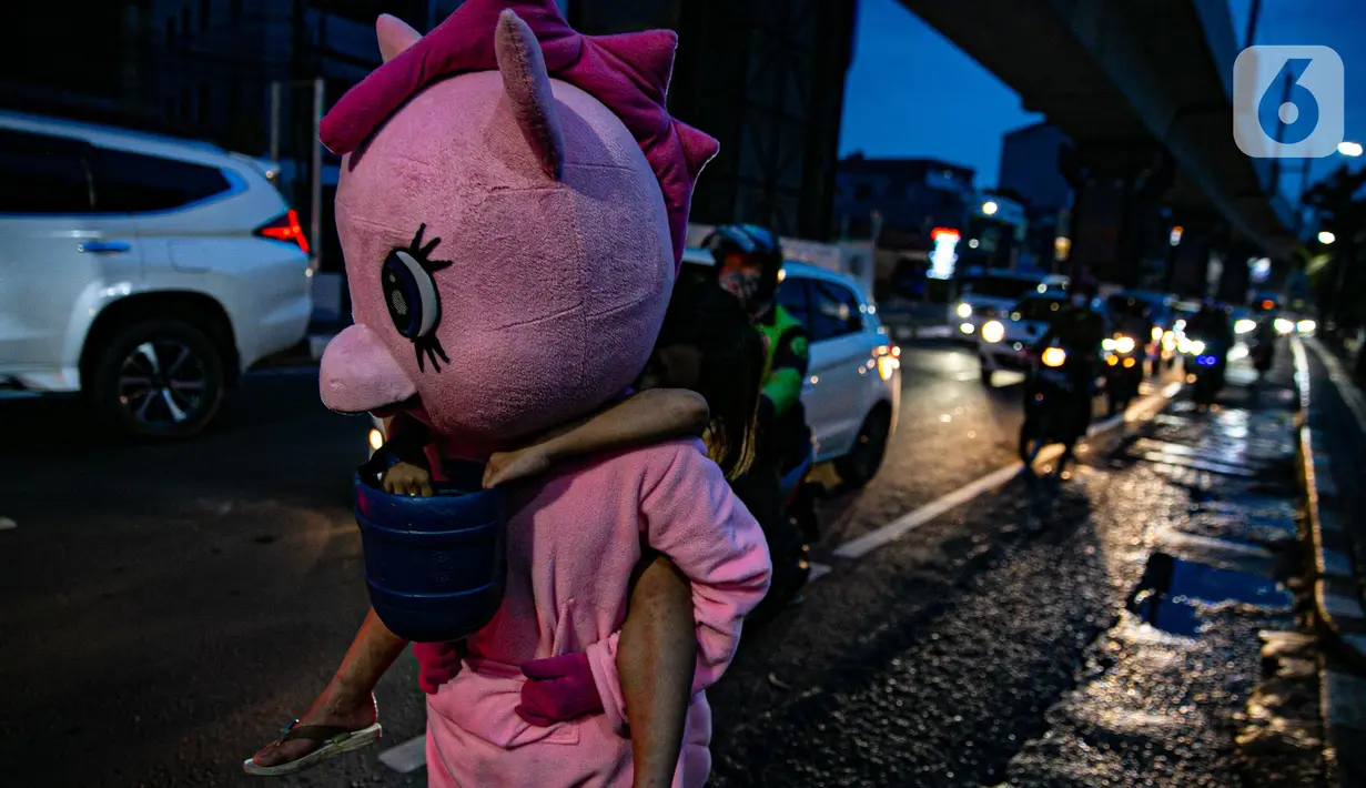 Warkuatno (41) bersama anak sulungnya, Bunga (9) berjalan kaki di pinggir Jalan Raya Fatmawati, Jakarta, Rabu (6/1/2021). Mantan sopir Metromini 75 ini menjadi badut keliling sejak bulan Maret lalu, tak lama setelah kasus corona COVID-19 terdeteksi di Indonesia. (Liputan6.com/Faizal Fanani)