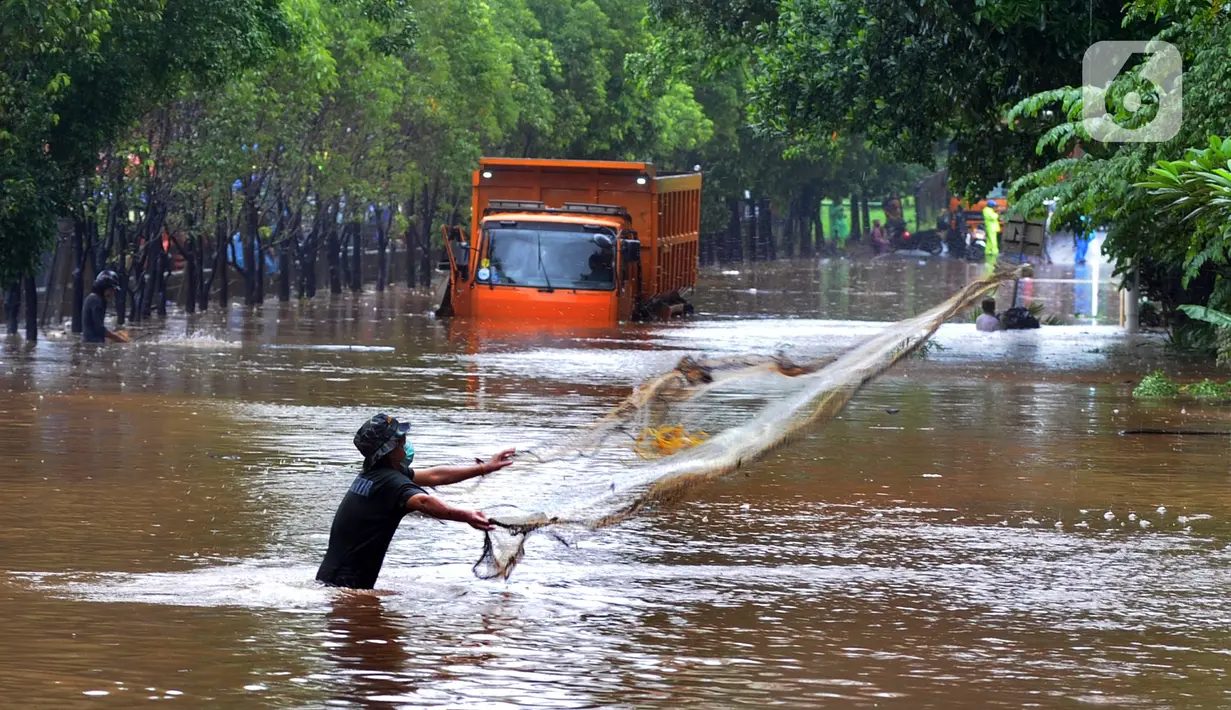 Warga menjala ikan di tengah jalan yang tertutup banjir di kawasan TB Simatupang, Jakarta Selatan, Sabtu (20/2/2021). Banjir terjadi akibat luapan Kali Serua yang berada di pinggir jalan tol. (merdeka.com/Arie Basuki)