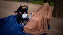 Dua penggemar kerajaan duduk di sepanjang rute Penobatan Raja di The Mall di London, Selasa, 2 Mei 2023. (AP Photo/Emilio Morenatti)