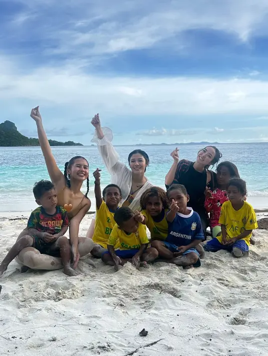 Gisella dan Naysila tampak berbaur dengan anak-anak lokal di pantai berpasir putih. Mereka duduk bersama sambil bermain dan tertawa, menunjukkan kehangatan dan kebersamaan yang tulus di tengah keindahan alam. (Liputan6.com/IG/@gisel_la)