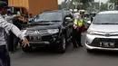 Petugas polisi lalu lintas memberhentikan kendaraan saat pemberlakuan sistem ganjil genap di pintu masuk Gardu Tol Cibubur 2, Jakarta, Senin (16/4). Aturan ini berlaku untuk kendaraan pribadi atau golongan I dan II. (Liputan6.com/Faizal Fanani)