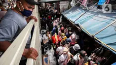 Seorang pria mengamati dari atas kerumuman pengunjung yang memadati Pasar Tanah Abang, Jakarta Pusat, Minggu (2/5/2021). Pusat Grosir Pasar Tanah Abang ramai didatangi pengunjung yang berbelanja menjelang Lebaran dengan berdesak-desakan tanpa jaga jarak. (Liputan6.com/Johan Tallo)