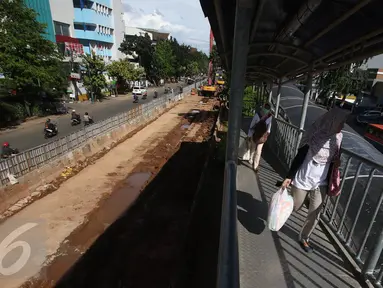 Penumpang bus transjakarta berjalan di samping pembangunan proyek underpass Matraman di Jakarta, Rabu (5/4). Proyek senilai Rp118 miliar itu ditargetkan selesai pada akhir 2017. (Liputan6.com/Immanuel Antonius)