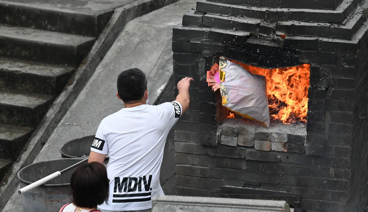 Orang-orang membakar persembahan untuk memberi penghormatan kepada orang tercinta yang telah meninggal di Pemakaman China Cape Collinson, dekat Chai Wan, Hong Kong, 5 April 2021. Kegiatan ini untuk menandai Festival Ching Ming yang juga dikenal sebagai pembersihan makam. (Peter PARKS/AFP)