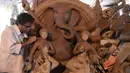 Seorang seniman India menyelesaikan pembuatan patung Dewa Hindu, Lord Ganesh di sebuah lokakarya di Hyderabad (19/8/2019). Patung ini dibuat dengan bahan-bahan ekologis untuk mengurangi polusi selama perendaman untuk festival Ganesh Chaturthi. (AFP Photo/Noah Seelam)