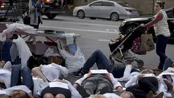 Seorang wanita melihat ratusan orang bergeletakan di jalanan New York, Kamis (29/10/2015). Aksi ini juga sebagai protes terhadap intervensi militer Rusia kepada Suriah beberapa tahun lalu. (REUTERS/Carlo Allegri)