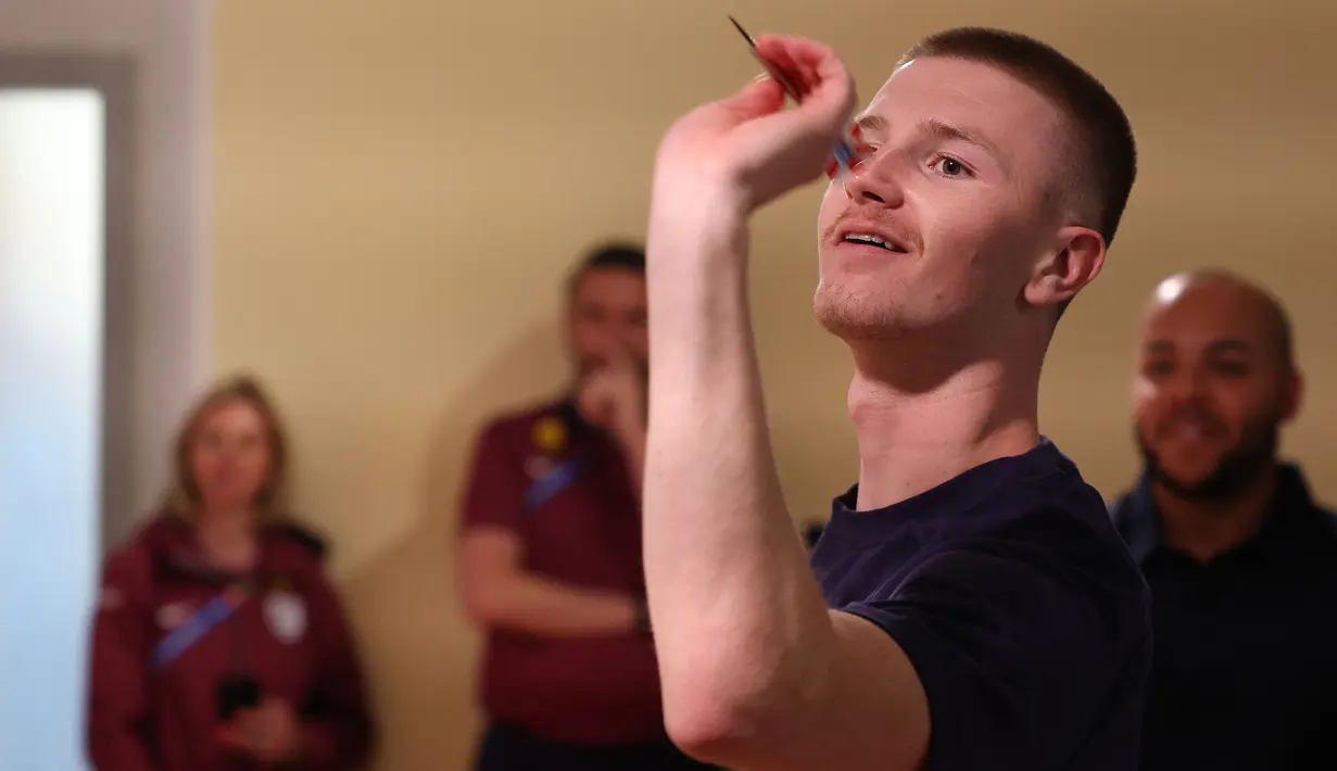 Pemain muda Timnas Inggris, Adam Wharton bermain Darts melawan jurnalis saat konferensi pers menjelang Euro 2024 di Blankenhain, Thuringia, Rabu (12,/06/2024) waktu setempat. (AFP/Adrian Dennis)