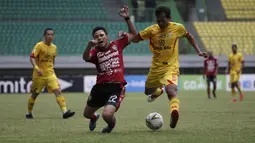 Gelandang Bhayangkara FC, Adam Alis, berebut bola dengan bek Bali United, Dias Angga, pada laga Shopee Liga 1 di Stadion Patriot Chandrabhaga, Bekasi, Jumat (13/9). Bhayangkara bermain imbang 0-0 atas Bali United. (Bola.com/Yoppy Renato)