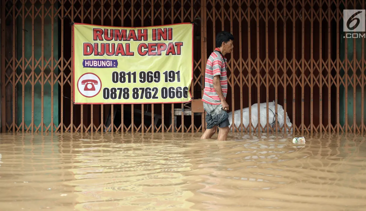 Warga berjalan melintasi banjir di Jalan Jatinegara Barat, Jakarta Timur, Selasa (6/2). Akibat banjir ini ruas jalan tersebut tidak dapat dilalui kendaraan. (Liputan6.com/Arya Manggala)