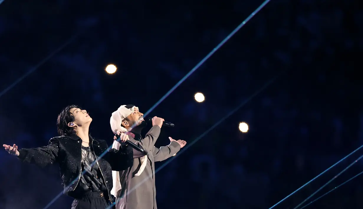 <p>Penyanyi Korea Selatan Jungkook bersama penyanyi Qatar Fahad Al-Kubaisi saat membawakan soundtrack FIFA World Cup Official yang berjudul Dreamers dalam upacara pembukaan Piala Dunia Qatar 2022, di Stadion Al Bayt di Al Khor, Qatar, Minggu (20/11/2022). (AFP/Karim Jaafar)</p>