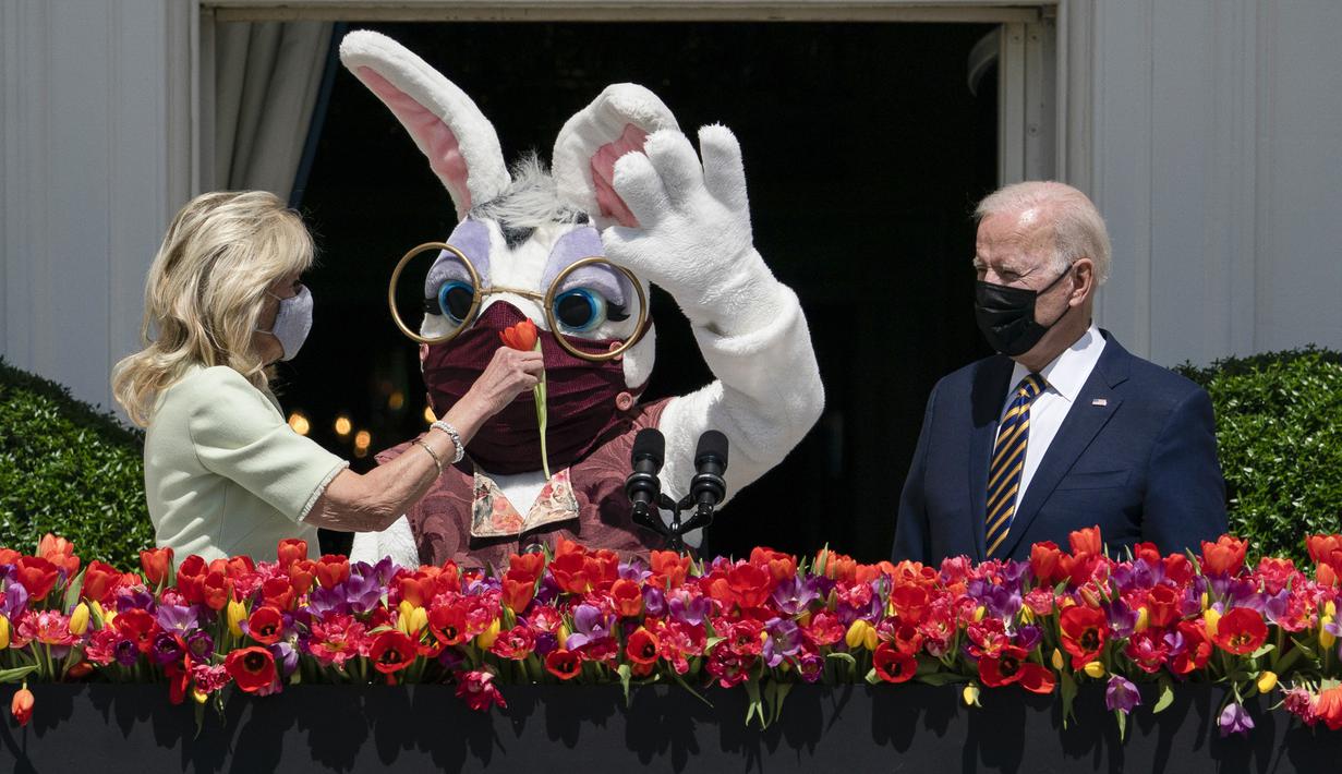Presiden Joe Biden menyaksikan Ibu Negara Jill Biden menyerahkan bunga kepada Kelinci Paskah selama acara Paskah di Gedung Putih, Washington, Amerika Serikat, Senin (5/4/2021). Gedung Putih kembali meniadakan tradisi Easter Egg Roll menyusul pandemi COVID-19. (AP Photo/Evan Vucci)