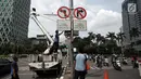 Petugas Dishub menurunkan rambu larangan melintas untuk sepeda motor di Jalan MH Thamrin hingga Jalan Medan Merdeka Barat, Jakarta Pusat, Rabu (10/1). (Liputan6.com/Arya Manggala)