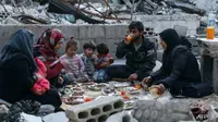 Sebuah keluarga di Idlib, Suriah berbuka puasa di tengah puing-puing sisa rumah mereka yang hancur. (AFP/AAREF WATAD)