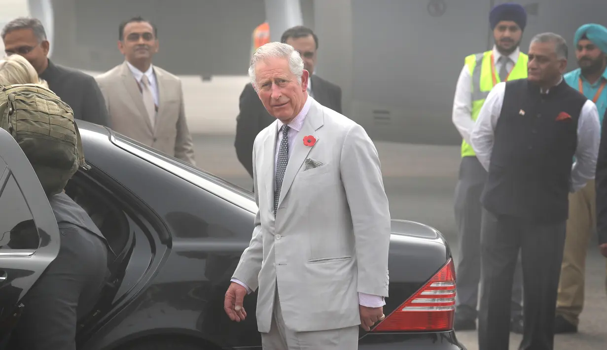 Pangeran Charles bersiap menaiki mobil setelah turun dari sebuah pesawat, bersama sang istri, Camilla di New Delhi yang diselimuti kabut asap, Rabu (8/11). Pasangan dari Kerajaan Inggris itu akan berada di India selama dua hari. (AP Photo/Manish Swarup)