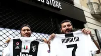 Suporter memperlihatkan jersey Juventus atas nama Cristiano Ronaldo di depan toko resmi klub di Turin, Selasa (10/7). Ronaldo akan diperkenalkan secara resmi ke publik sebagai pemain Juventus pada Senin depan. (AFP PHOTO / Isabella Bonottovv)