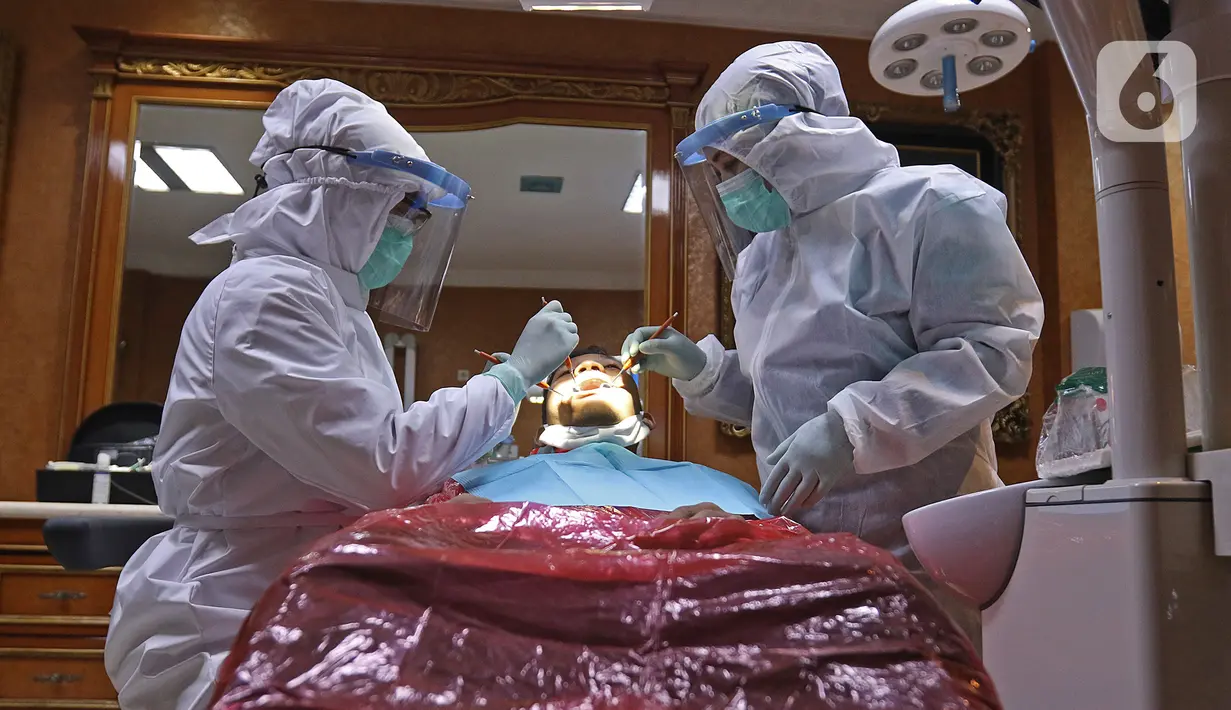 drg. Ayusha (kiri) mengenakan alat perlindungan diri (APD) saat memeriksa pasien di salah satu klinik di kawasan Pulo Gadung, Jakarta, Rabu (22/4/2020). Penggunaan APD dilakukan sebagai SOP pemeriksaan gigi saat pandemi serta mengantisipasi penularan COVID-19. (Liputan6.com/Herman Zakharia)