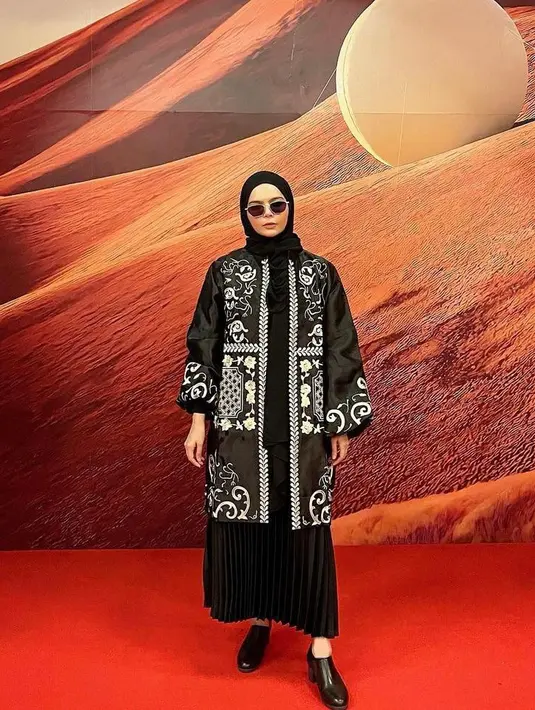 Tampil modis dengan kombinasi tunik warna hitam dan detail bordir bersama rok plisket warna senada. Makin kece jika ditambah aksesori berupa kacamata! (Instagram/mrsvivi).