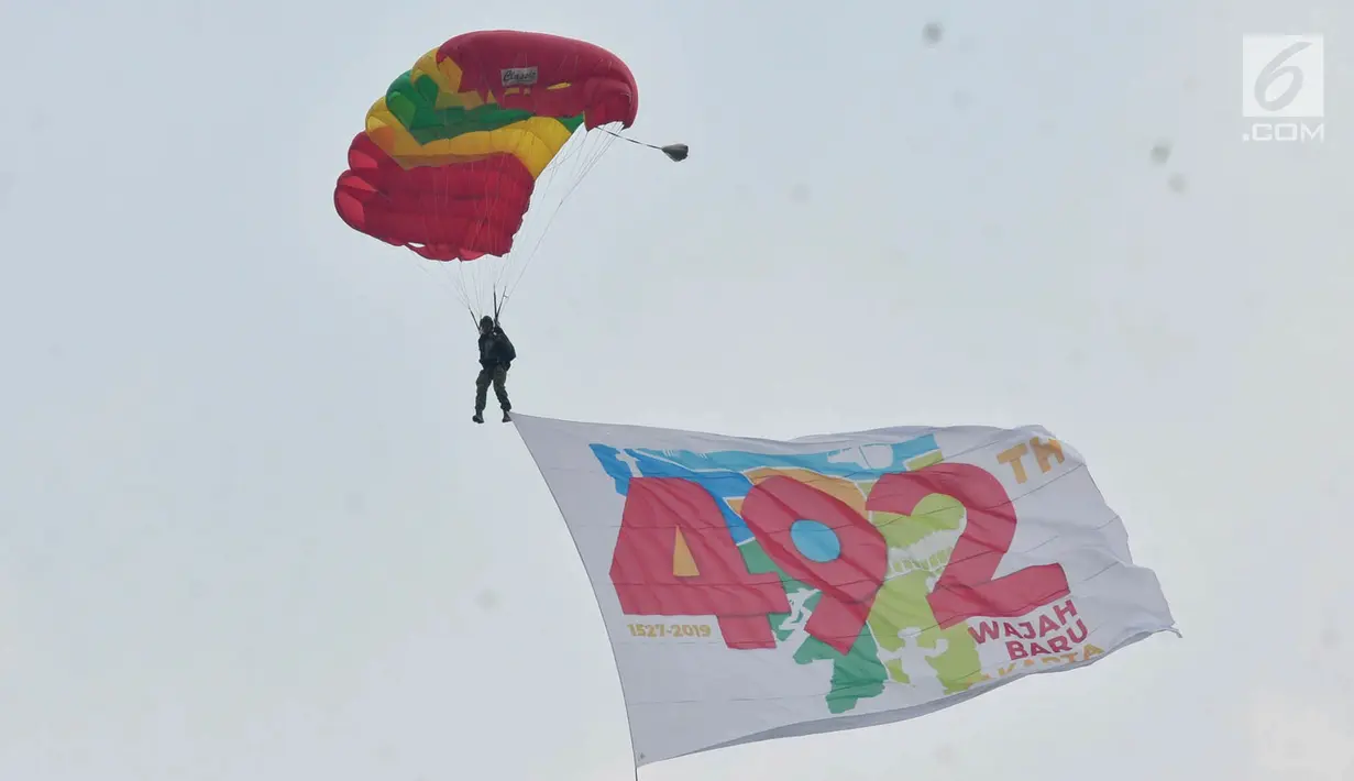 Penerjun payung membawa bendera HUT ke-492 DKI Jakarta saat Festival Damai Millenial Road Safety di Monas, Jakarta, Minggu (23/6/2019). Aksi ini diikuti puluhan penerjun payung dari personel gabungan TNI-Polri. (merdeka.com/Iqbal Nugroho)