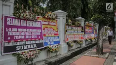 Pejalan kaki melintasi karangan bunga bertuliskan ucapan selamat untuk Joko Widodo (Jokowi) dan Ma'ruf Amin di gedung Sekretariat Negara, Jakarta, Senin (22/4). Karangan bunga dari pendukung Jokowi-Ma'ruf tersebut ditujukan atas kemenangan pasangan itu pada Pilpres 2019. (Liputan6.com/Faizal Fanani)