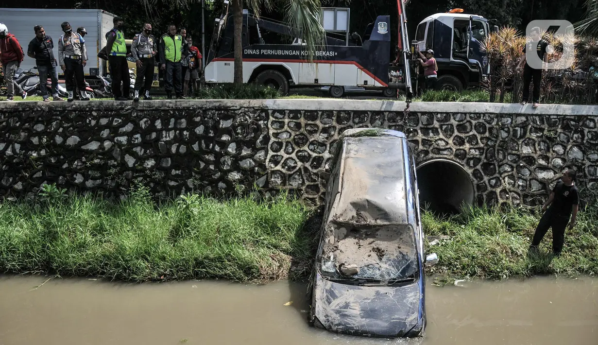Petugas Dinas Perhubungan Kota Bekasi saat evakuasi mobil yang terperosok ke kali di Harapan Indah, Bekasi, Jawa Barat, Rabu (16/2/2022). Beruntung tidak ada korban jiwa dalam kejadian tersebut, namun mobil mengalami rusak parah. (merdeka.com/Iqbal S. Nugroho)