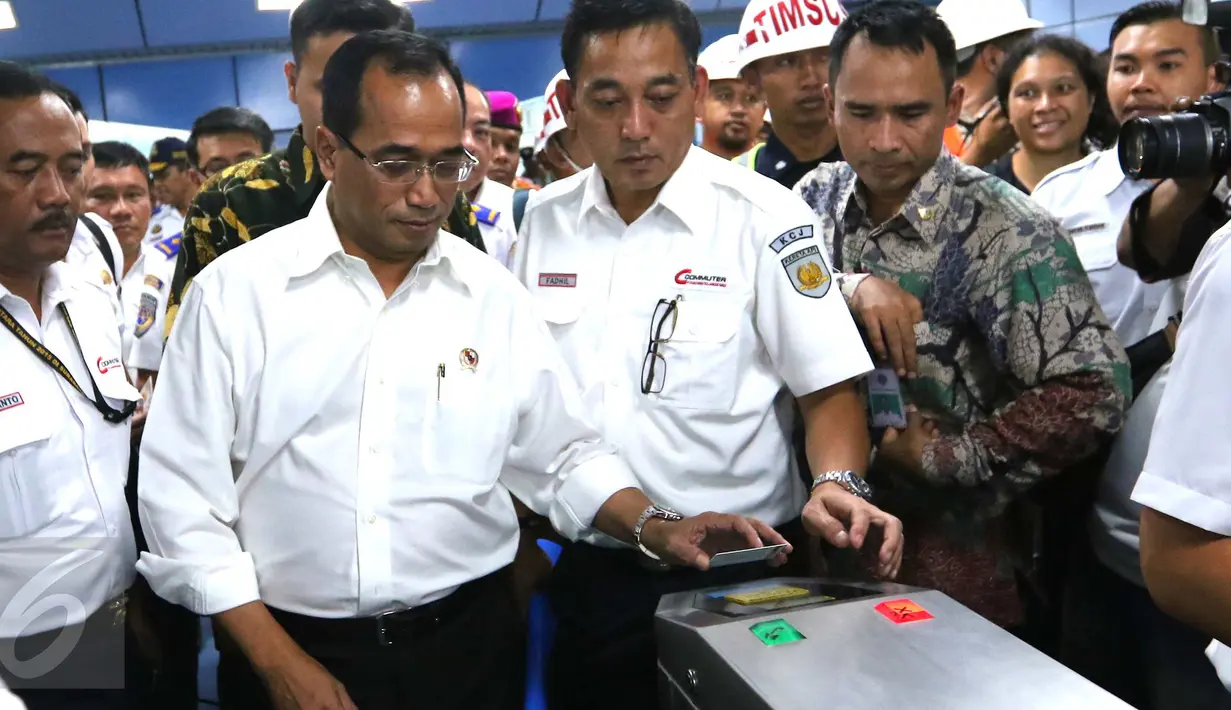 Menhub Budi Karya Sumadi menempelkan e-tiket pada reader gate sebelum naik KRL di Stasiun Juanda, Jakarta, Rabu (10/8). Menhub Budi meninjau proyek pembangunan kereta bandara Soekarno Hatta yang akan terintegrasi dari Jakarta. (Liputan6.com/Angga Yuniar)