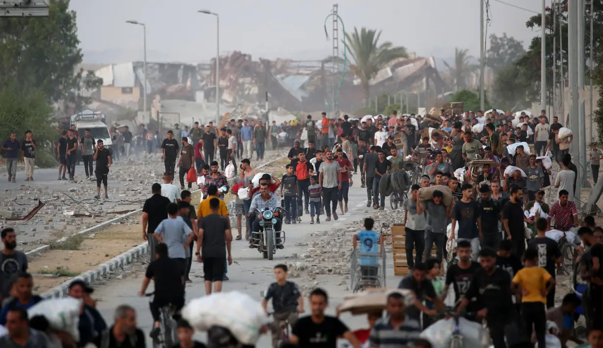 Warga Palestina berjalan di sepanjang jalan al-Rashid, Jabalia barat pada 23 Juli 2025, setelah menerima bantuan kemanusiaan dari titik distribusi bantuan di Jalur Gaza utara. (Eyad BABA/AFP)