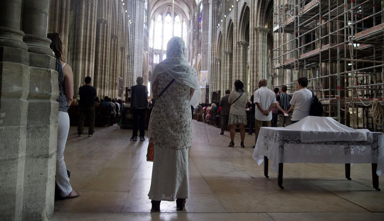 Seorang wanita muslim berdiri ketika menghadiri misa di Katedral Saint-Denis, dekat Prancis, Minggu (31/7). Muslim di penjuru Prancis menghadiri misa sebagai solidaritas atas pembunuhan seorang pastor oleh militan Islam. (Dominique Faget/AFP)