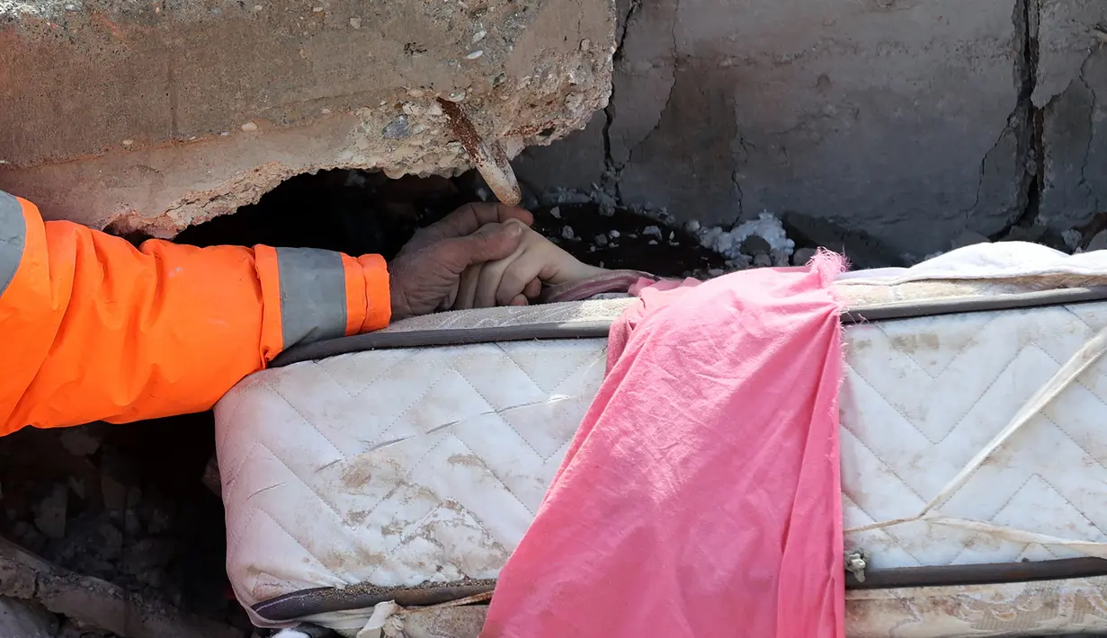 Mesut Hancer memegang tangan putrinya, Irmak (15), yang meninggal dalam gempa bumi di Kahramanmaras, Turki, 7 Februari 2023. "Ambil foto anakku," panggil Mesut Hancer dengan suara rendah bergetar kepada seorang fotografer media Prancis, AFP, yang melihatnya. (Adem ALTAN/AFP)