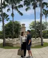 Enzy Storia liburan lebaran bersama suaminya ke Bali. Tampak ia mengenakan outer cardigan abu-abu dipadukan inner tanktop putih serta celana panjang hitam. Membawa tas tote bag besar, serta flat shoes putih. [@enzystoria]