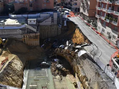 Sebuah jalanan ambles di distrik Balduina, kawasan barat ibu kota Italia, Roma, Kamis (15/2). Sedikitnya enam mobil terperosok ke dalam lubang berkedalaman 10 meter tersebut. (AFP PHOTO / TIZIANA FABI)