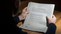 Seorang pria membaca iklan berisi permintaan maaf di sebuah surat kabar Inggris, 25 Maret 2018. CEO Facebook Mark Zuckerberg meminta maaf terhadap skandal Cambridge Analytica menggunakan iklan di sembilan surat kabar Inggris dan AS. (Oli SCARFF/AFP)