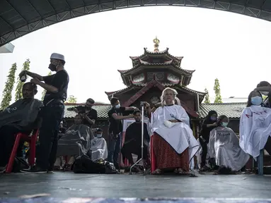 Penata rambut memberikan potongan rambut gratis sebagai bagian dari amal Muslim untuk yang membutuhkan saat umat Islam di seluruh dunia merayakan bulan suci Ramadhan di Muhammad Cheng Hoo di Surabaya (18/4/2022). (AFP/Juni Kriswanto)