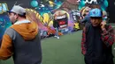 Wisatawan berfoto di depan karya seni grafiti pada festival pekan grafiti di Mexico City, Meksiko, Minggu (9/10). Grafiti merupakan salah satu seni jalanan yang populer hingga kini. (REUTERS/Carlos JASSO)