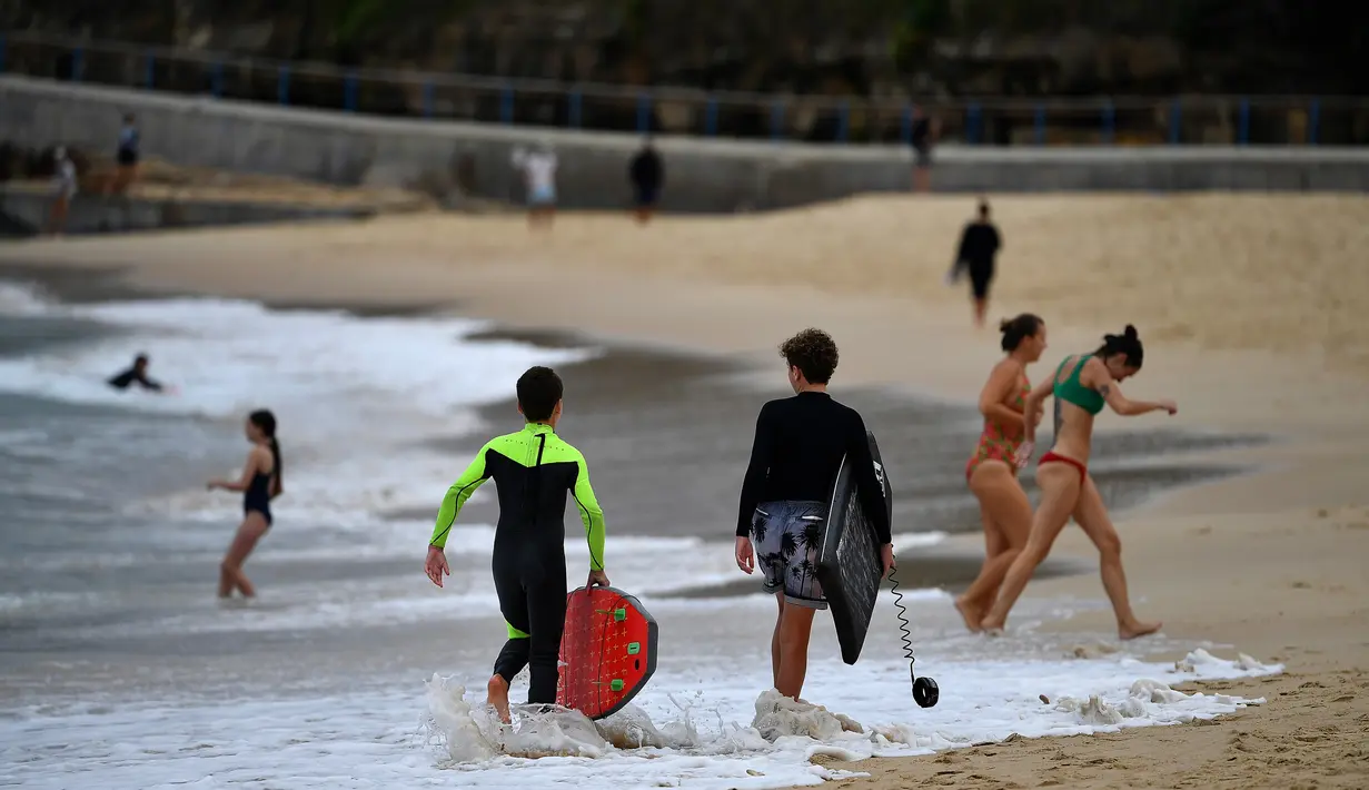 Orang-orang berjalan-jalan di Pantai Maroubra yang dibuka kembali untuk aktivitas warga di tengah pembatasan sosial yang diberlakukan di kala wabah corona (Covid-19) di Sydney, Australia (20/4/2020). (AFP/Saeed Khan)