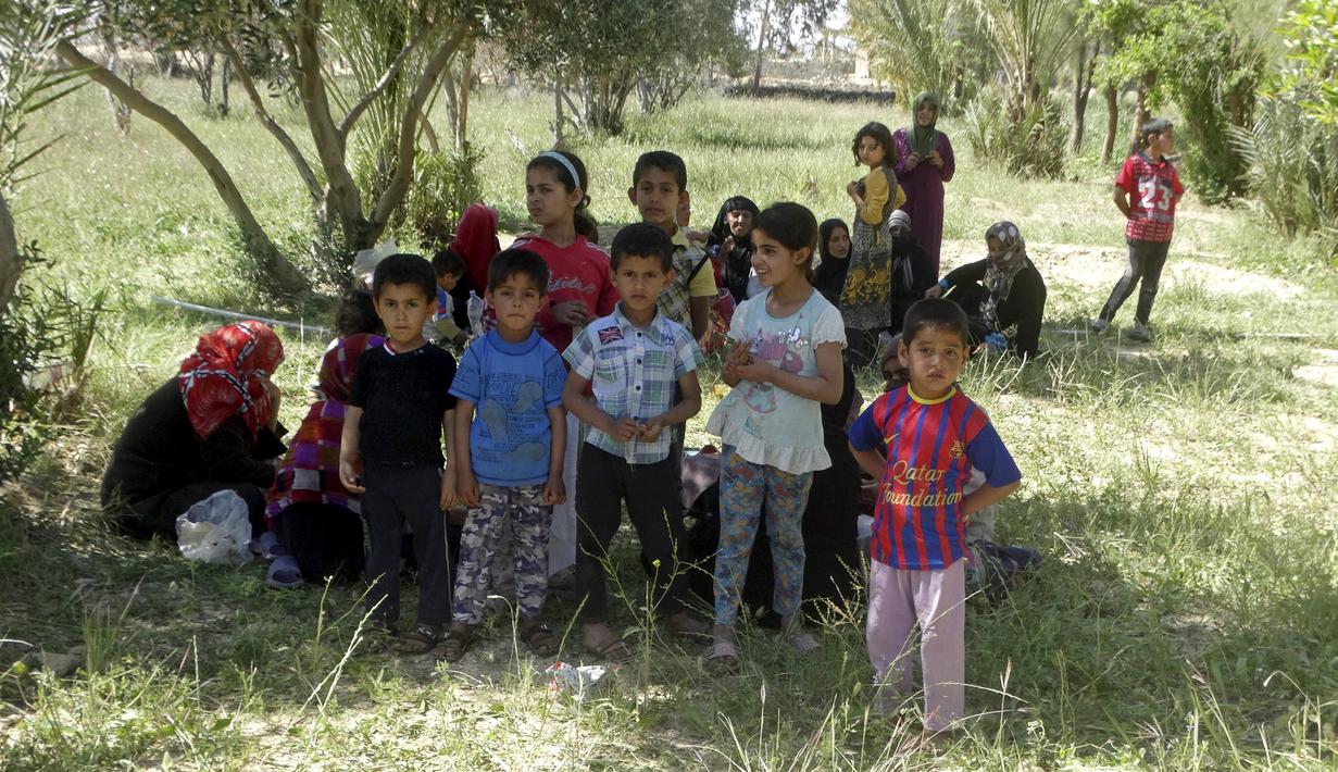 Sejumlah anak-anak beristirahat dibawah pohon setelah berjalan ketika melarikan diri akibat pertempuran antara pasukan Irak dan militas ISIS di kota Hit, provinsi Anbar, (5/4/2016). (REUTERS/Stringer)