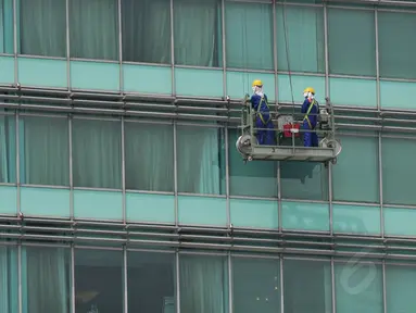 Pekerja terlihat tengah membersihkan kaca gedung di Bundaran HI, Jakarta, dengan menggunakan gondola, Senin (8/9/14). (Liputan6.com/Johan Tallo)
