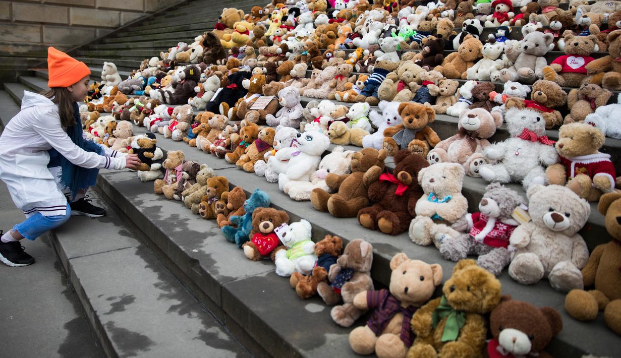 Seorang siswa meletakkan satu boneka beruang atau Teddy Bears di tangga Concert Hall, Berlin, Kamis (15/3). Kelompok bantuan kemanusiaan World Vision melakukan aksi pengumpulan 740 boneka beruang. (AFP PHOTO/Odd ANDERSEN)